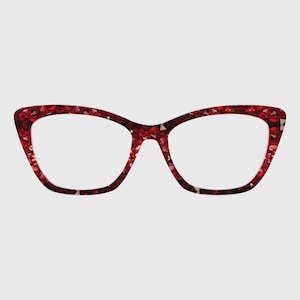 Peut inclure: Lunettes de forme œil-de-chat avec une monture rouge vif présentant une texture facettée rappelant celle d'une pierre précieuse. Le design affiche une silhouette angulaire audacieuse avec une palette de couleurs cramoisi et un motif cristallin.