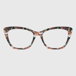 May include: Cat-eye glasses frames featuring a dark navy blue background with a repeating pattern of orange pumpkins, white pumpkins, and various colorful autumn flowers including deep red and yellow floral accents across the entire frame.