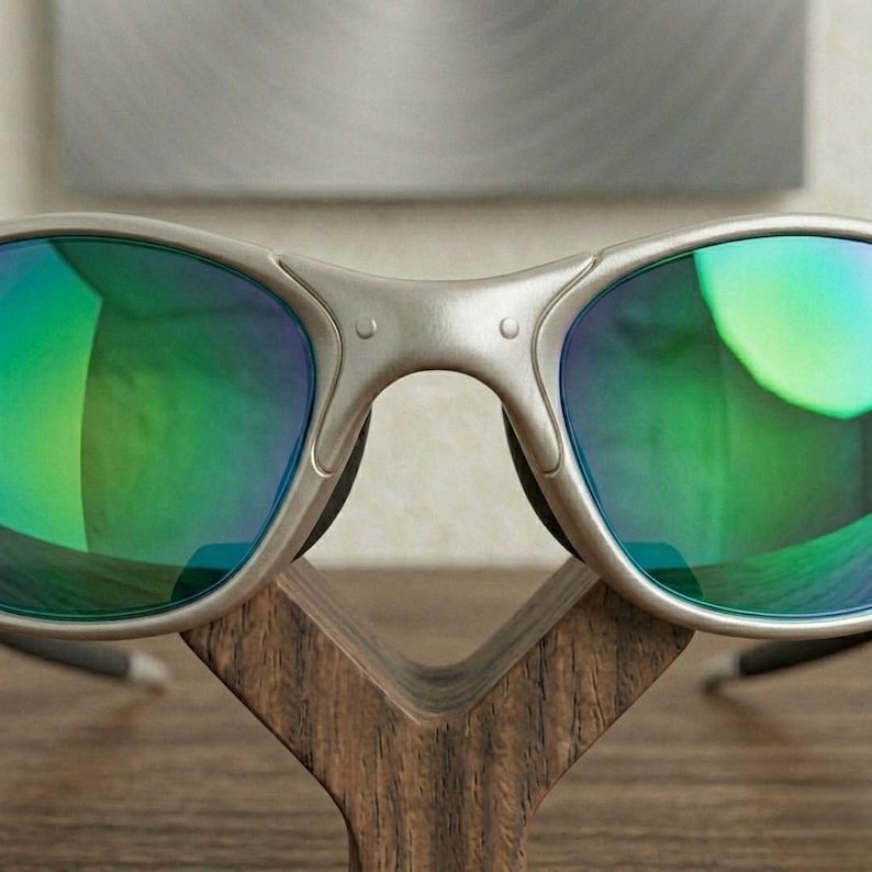 May include: Silver-framed sunglasses with green and blue reflective lenses. The sunglasses are displayed on a wooden stand. The lenses have a gradient effect, transitioning from green to blue. The frame has a matte finish.