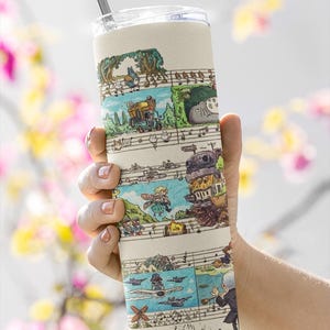 May include: A beige tumbler with a clear lid and a silver straw. The tumbler features a whimsical illustrated design of various characters and scenes, set against a musical staff background. The design includes a variety of colors.
