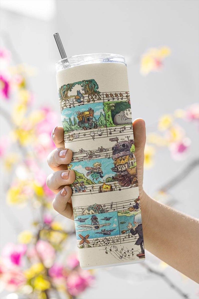 May include: A beige tumbler with a clear lid and a silver straw. The tumbler features a whimsical illustrated design of various characters and scenes, set against a musical staff background. The design includes a variety of colors.