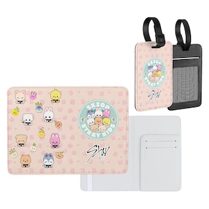 May include: A light pink passport holder and two luggage tags. The passport holder features cartoon characters and the text "SKZOO STAY". One luggage tag is light pink, the other is black. Both have the same cartoon design and text.