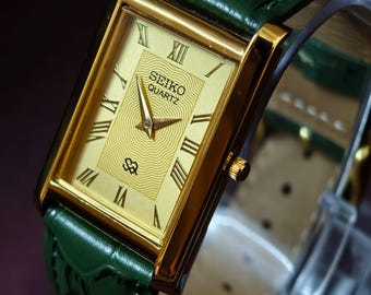Elegancki zegarek na rękę Seiko Slim Tank w stylu vintage, z tarczą w kolorze złotym i zielonym paskiem skórzanym