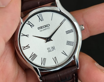 Relógio de pulso vintage Seiko Slim Quartz com mostrador branco e caixa circular prateada.