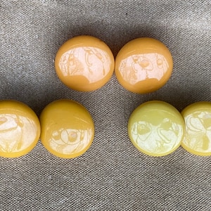 May include: Set of six yellow and light yellow round ceramic buttons. The buttons have a glossy finish and a slightly raised design.