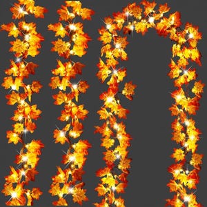 Op de afbeelding: Een kunstmatige esdoornblad-slinger met levendige oranje, gele en rode bladeren, verweven met kleine, warmwitte LED-lampjes. De flexibele rankstructuur maakt verschillende opstellingen van de herfstbladeren mogelijk voor decoratieve doeleinden.