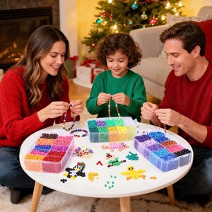 May include: A collection of colorful plastic pony beads organized in three clear plastic storage containers on a white table. The set includes various loose beads and assembled shapes like a penguin and a yellow bird, alongside stringing cord.