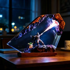 Puede incluir: Lámpara decorativa de resina con base de madera, que representa una escena con una figura mandaloriana y un pequeño extraterrestre verde. La lámpara tiene un cuerpo de resina transparente y en ángulo con un interior colorido e iluminado. La escena muestra una batalla con luz brillante.