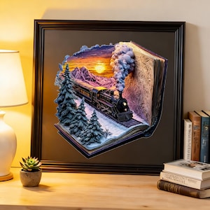 Puede incluir: Obra de arte enmarcada que representa un tren que emerge de un libro, ambientada en una puesta de sol sobre montañas nevadas y árboles de hoja perenne. El tren es negro con humo blanco, enmarcado en un borde marrón oscuro.
