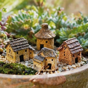May include: Miniature fairy garden houses with textured roofs and stone-like walls. The houses are in various shapes and sizes, with a natural, earthy color palette. They are set among small pebbles and greenery.