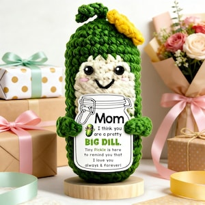 May include: A green crocheted pickle figure with a smiling face and a yellow accent. The pickle holds a sign that reads "Mom, I think you are a pretty BIG DILL. I love you always & forever!" with a jar illustration.