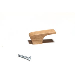 May include: A light-colored wooden cabinet pull with a curved design. The pull is accompanied by a silver screw, suggesting easy installation. This hardware is suitable for drawers and cabinets.