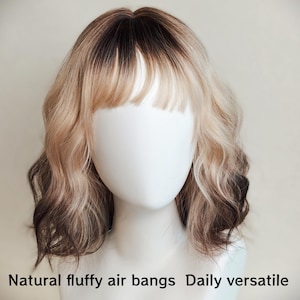 K&ouml;nnte beinhalten: Eine schulterlange Per&uuml;cke mit welligem, gestuftem Haar, das einen dunklen braunen Ansatz und einen &Uuml;bergang zu hellem Blond aufweist. Der Stil umfasst einen nat&uuml;rlichen, luftigen Pony. Der Text Natural fluffy air bangs Daily versatile ist unten zu sehen.