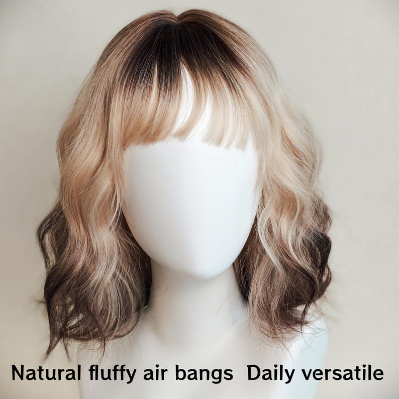 K&ouml;nnte beinhalten: Eine schulterlange Per&uuml;cke mit welligem, gestuftem Haar, das einen dunklen braunen Ansatz und einen &Uuml;bergang zu hellem Blond aufweist. Der Stil umfasst einen nat&uuml;rlichen, luftigen Pony. Der Text Natural fluffy air bangs Daily versatile ist unten zu sehen.