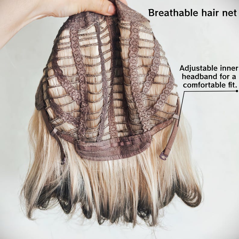 K&ouml;nnte beinhalten: Das Innere einer Per&uuml;cke mit atmungsaktivem Haarnetz und verstellbarem Innenband f&uuml;r einen bequemen Sitz. Die Per&uuml;cke hat blondes Haar mit dunklen Ans&auml;tzen und dunklen Spitzen und zeigt die Konstruktion der Kappe mit braunen Stoffstreifen.