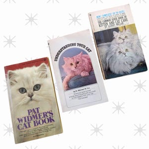 Puede incluir: Se muestran tres libros antiguos sobre el cuidado de gatos. Los libros presentan imágenes de gatos esponjosos y títulos como "Understanding Your Cat" y "The Common Sense Book of Kitten and Cat Care". Los libros están ilustrados.