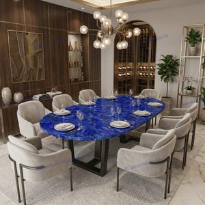 May include: A dining room set featuring a large, oval-shaped table with a vibrant blue, textured surface. The table is surrounded by ten beige upholstered chairs with dark metal frames. A gold chandelier hangs above, illuminating the room.