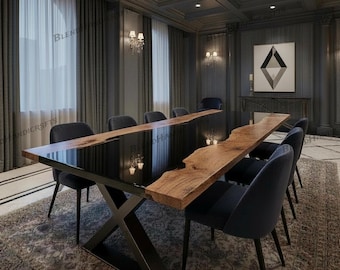 May include: A contemporary dining table with a black, reflective surface and a natural wood edge. The table is supported by a black metal X-shaped base. Dark blue chairs surround the table. The room features dark grey walls and a patterned rug. The table is approximately 300 cm long.