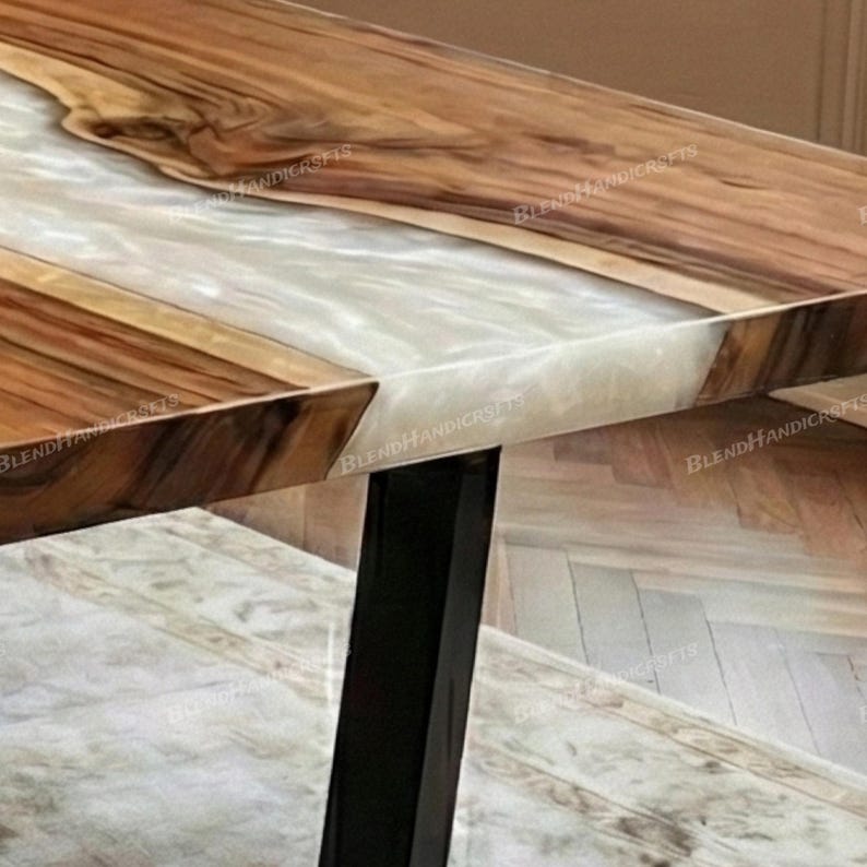 May include: Close-up of a wooden table with a white resin inlay. The table features a natural wood grain pattern with a glossy finish. The table has black metal legs and is a unique piece of furniture.