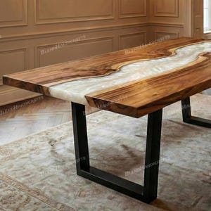 May include: A rectangular wooden dining table with a white resin river design. The table has a natural wood grain finish and sits on black metal legs. The table is approximately 72 inches long.