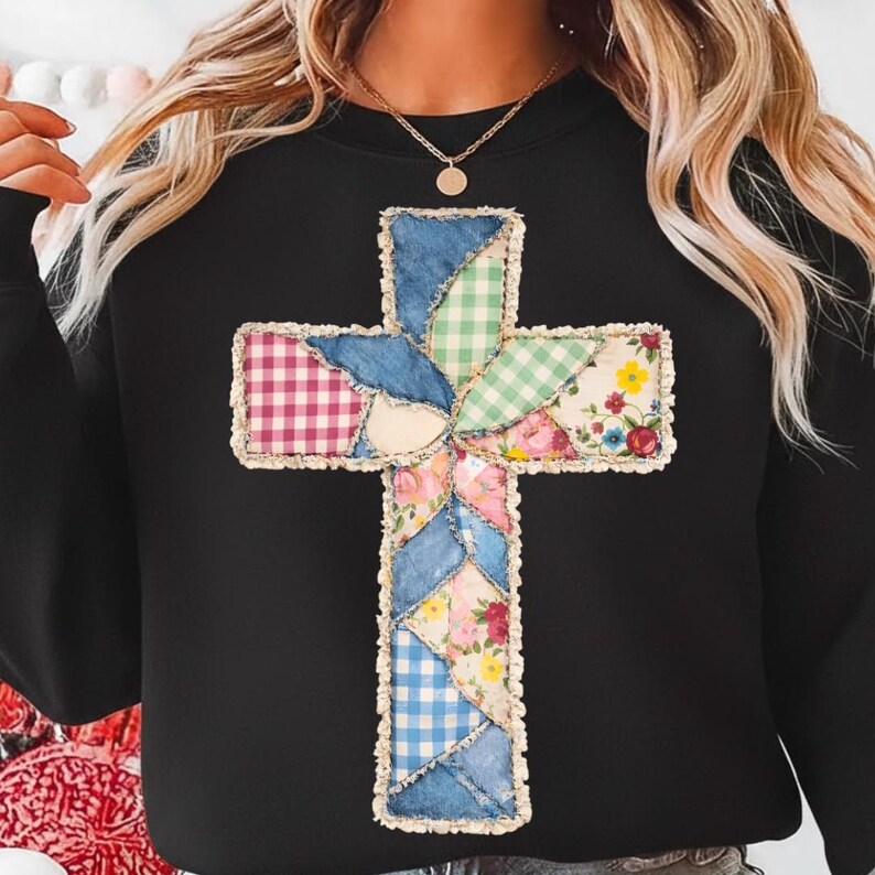May include: Black sweatshirt with a patchwork cross design. The cross is made from denim, gingham, and floral fabrics. The cross is centrally placed on the sweatshirt, creating a unique and visually appealing design. The sweatshirt is a comfortable garment.