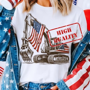 May include: White t-shirt featuring a detailed illustration of an excavator with an American flag draped over it. The design includes the text "HIGH QUALITY" in a red stamp. The shirt is a patriotic design.
