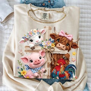 May include: Cream-colored sweatshirt featuring a cross design with a lamb, cow, pig, and rooster. The animals are adorned with floral accents and bows. The sweatshirt has a gold chain and the Comfort Colors logo.