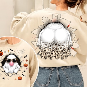 May include: A beige sweatshirt featuring a graphic of a ghost wearing sunglasses and blowing a pink bubble gum bubble, surrounded by pumpkins, spiders, and webs. The back design shows a ghost with a leopard print skirt emerging from a tear.