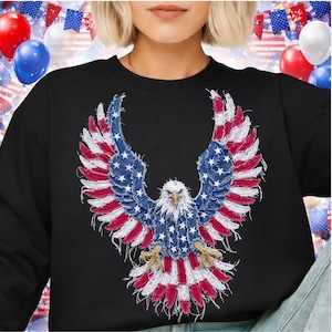 May include: Black sweatshirt featuring a patriotic eagle design. The eagle's wings and body are crafted with a denim-like texture, incorporating the American flag's stars and stripes in red, white, and blue. The eagle's head is white with a yellow beak.