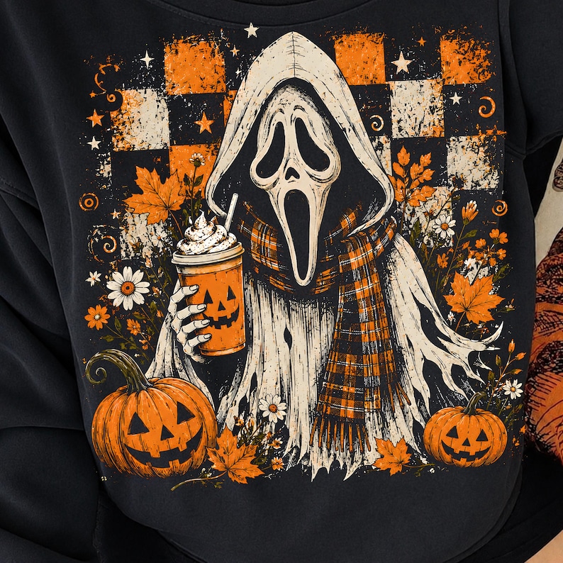 May include: A black sweatshirt featuring a graphic of a hooded ghost figure wearing a plaid scarf and holding a pumpkin-faced cup. The design includes orange and white checkered patterns, autumn leaves, daisies, and two jack-o'-lantern pumpkins.