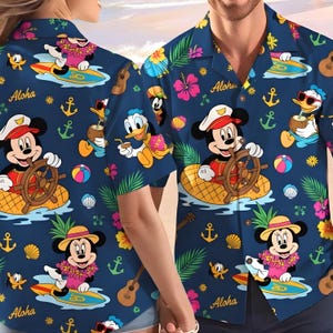 Könnte beinhalten: Marineblaues Hawaiihemd mit Disney-Figuren, darunter Mickey und Minnie Mouse und Donald Duck. Das Hemd hat ein tropisches Thema mit floralen und nautischen Elementen, darunter Anker und Surfbretter. Das Wort "Aloha" ist auf dem Hemd aufgedruckt.