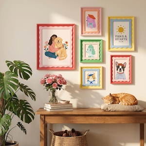 May include: A gallery wall arrangement featuring six scalloped-edge frames in various colors. The artwork includes illustrations of a person with a golden retriever, a dog in a beret, a poodle, a cat in a sailor hat, a French bulldog, and text reading PAWS & HEARTS CLUB.