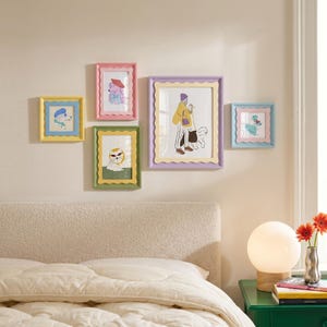 Puede incluir: Una colección de cinco marcos de pared rectangulares con bordes festoneados en amarillo, rosa, verde, lavanda y azul claro. Cada marco contiene una ilustración colorida con varios personajes, incluidos animales y personas, exhibidos en una pared.
