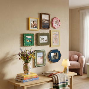 Puede incluir: Una composición de pared con ocho marcos de fotos variados en diferentes formas, colores y texturas, incluyendo diseños festoneados, con cuentas y rectangulares, junto a un jarrón de cerámica con flores.