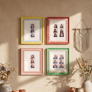 May include: Four colorful picture frames with scalloped edges are displayed on a wall. Each frame holds multiple small portrait photos. The frames are in shades of yellow, coral, pink, and green, with white matting.