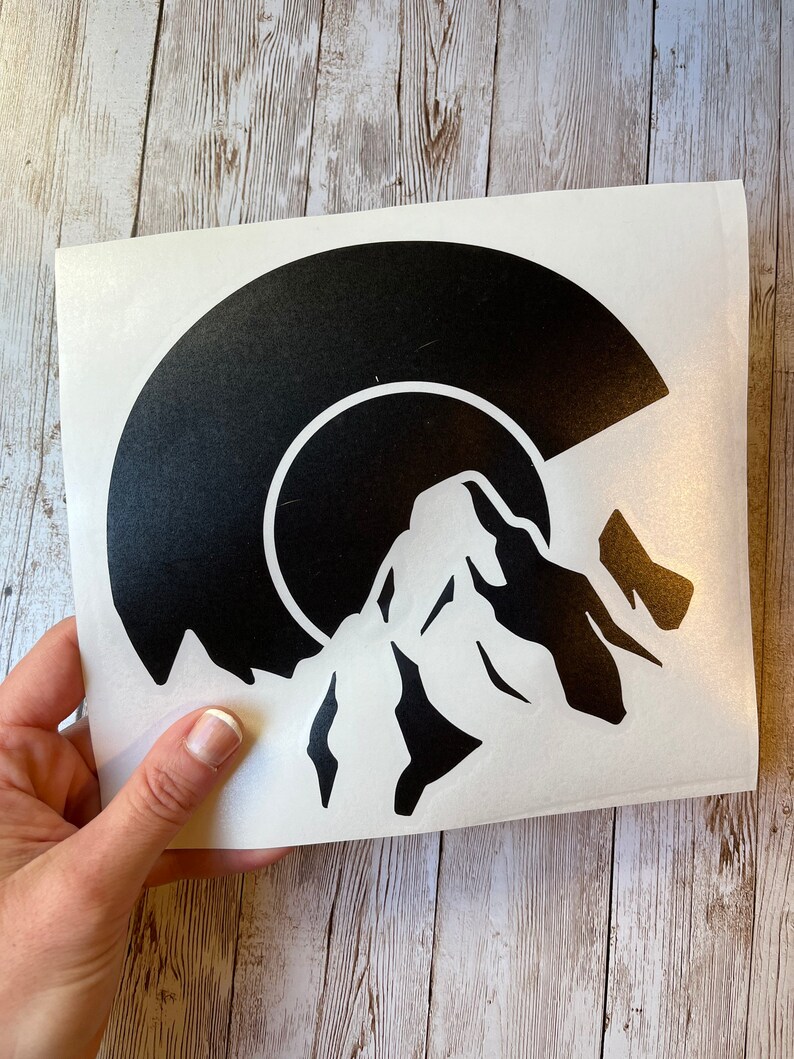 May include: A black vinyl record sticker with a mountain silhouette design. The record is partially visible, with the mountain silhouette rising above it.