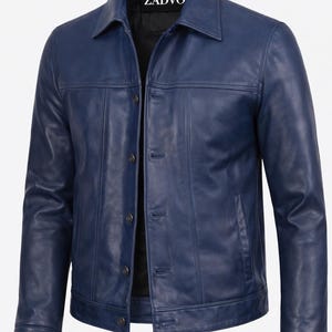 May include: A navy blue leather jacket with a button-up front, collared neckline, and two front pockets. The jacket has vertical stitching details and the brand name "ZADVO" is visible on the collar.