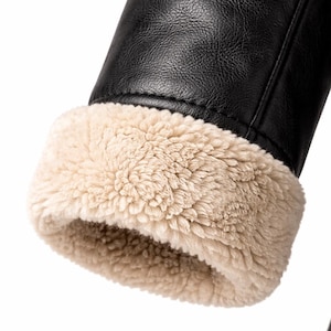 May include: Close-up of a black leather jacket sleeve with a beige, fluffy, faux fur lining at the cuff. The jacket appears to be made of a smooth, durable material, and the fur adds a contrasting texture.
