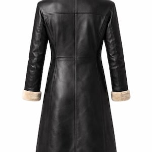 May include: A black leather coat with a beige faux fur collar and cuffs. The coat has a long, tailored silhouette with visible stitching details. The back view showcases the coat's design and structure, suitable for cold weather.