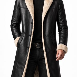 May include: A long black leather coat with a beige shearling collar and lining. The coat has a button closure, pockets, and a belt. The coat is a classic outerwear piece.