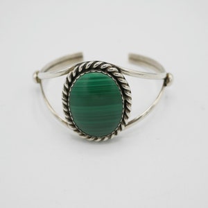 May include: A silver bracelet featuring a green malachite stone set in a rope-like design.
