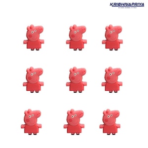 Puede incluir: Nueve dijes de zapatos de cerdo de dibujos animados rosas sobre un fondo blanco. Cada dije presenta un cerdo sonriente con brazos y piernas pequeños. Los dijes son de un tono rosa vibrante.