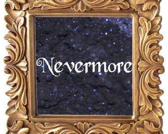 May include: Ornate gold-colored frame with intricate scrollwork. The frame surrounds a dark background with the word "Nevermore" in white script. The background has a speckled, glittery appearance.