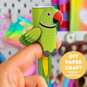 May include: A green paper parrot finger puppet craft featuring a red beak, a pink neck ring, and a yellow tail feather. The parrot has a cylindrical body designed to fit over a finger. A yellow circular graphic includes the text DIY PAPER CRAFT DIGITAL DOWNLOAD.