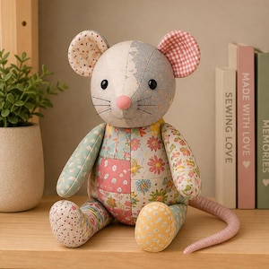 A single patchwork stuffed rat plush toy sitting on a wooden shelf next to a small potted plant and books.