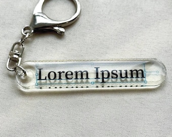 Llavero de Lorem Ipsum: chiste de diseñador gráfico, llavero acrílico ovalado con tipografía, regalo divertido para artistas, programadores y desarrolladores.