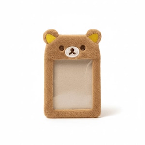 May include: A brown plush card holder shaped like a bear's face, with yellow accents on the ears. The card holder has a clear window for displaying a card or ID. The bear face has embroidered details.