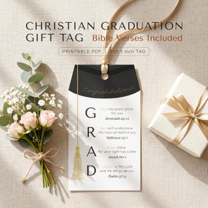 Könnte beinhalten: Ein christliches Abschlussgeschenk-Etikett mit Bibelversen, mit einem schwarz-goldenen Design. Das Etikett enthält das Wort "GRAD" mit inspirierenden Zitaten aus Jeremia, Hebräer, Jesaja und Psalmen. Ein kleiner Strauß rosa Rosen und eine Geschenkbox sind ebenfalls im Bild.