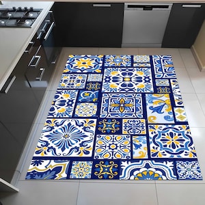 Peut inclure: Un tapis rectangulaire avec un motif de carreaux répété dans des tons de bleu, jaune et blanc. Le motif présente des motifs floraux et géométriques, créant un revêtement de sol vibrant et décoratif. Le tapis est posé sur un sol carrelé dans une cuisine.