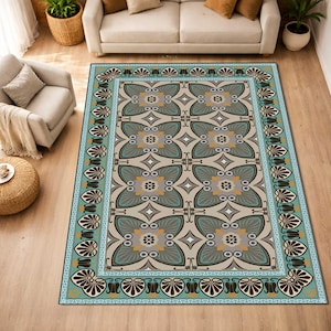 May include: A rectangular rug featuring a geometric floral design in grey, teal, and yellow. The rug has a teal border with a repeating shell design and a Greek key pattern. The rug is placed on a wooden floor.